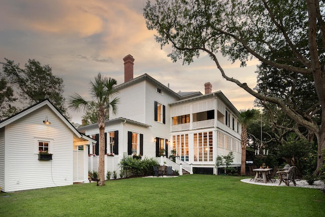 back house at dusk featuring a yard