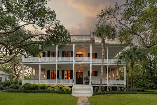 view of front of house with covered porch, a yard, a balcony, and ceiling fan