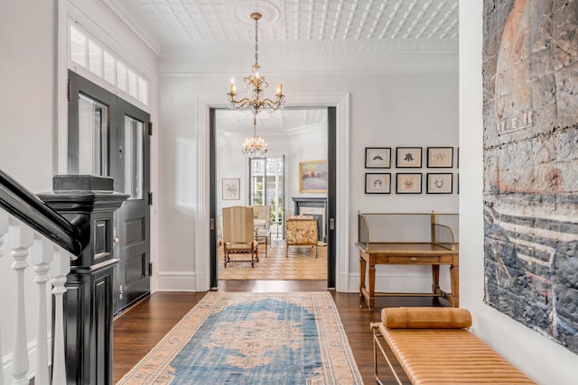 entryway featuring french doors, dark wood-type flooring, crown molding, and a notable chandelier