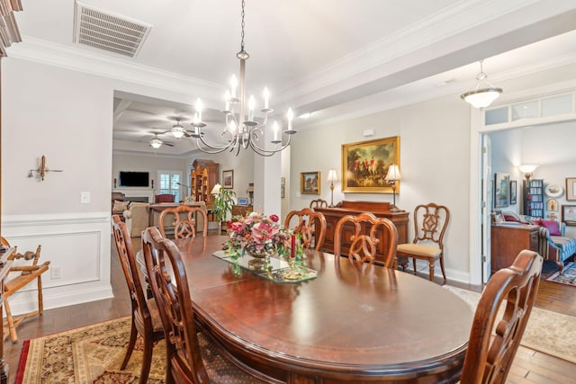 dining area with wood-type flooring, ceiling fan with notable chandelier, and ornamental molding