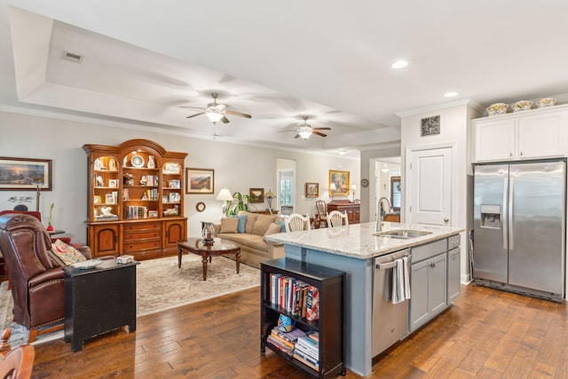 kitchen with a center island with sink, sink, dark hardwood / wood-style floors, white cabinetry, and stainless steel appliances