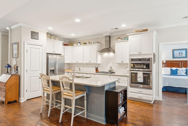 kitchen featuring white cabinetry, dark hardwood / wood-style flooring, wall chimney exhaust hood, and an island with sink