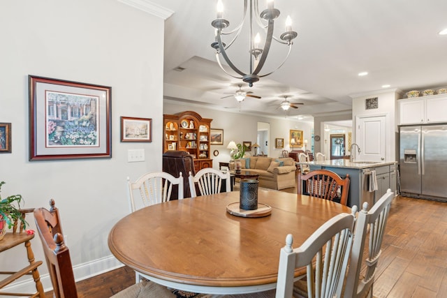 dining room featuring ceiling fan with notable chandelier, dark hardwood / wood-style floors, ornamental molding, and sink