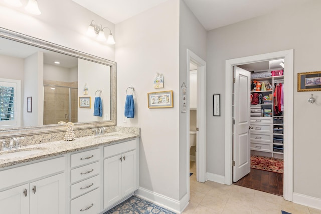 bathroom featuring toilet, vanity, tile patterned floors, and a shower with shower door