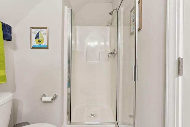 bathroom with toilet, a shower with shower door, and vaulted ceiling