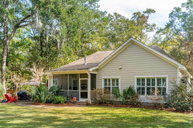 back of house featuring a lawn and a sunroom