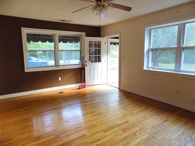 unfurnished room featuring light hardwood / wood-style floors, ceiling fan, and a textured ceiling