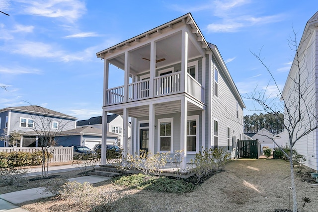 view of front of house with a ceiling fan, covered porch, fence, and a balcony