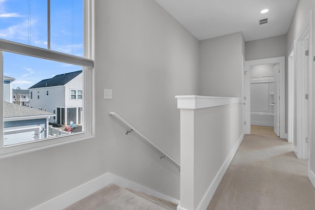 hallway with baseboards, visible vents, and an upstairs landing