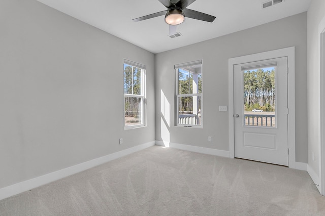 doorway featuring light carpet, baseboards, visible vents, and ceiling fan