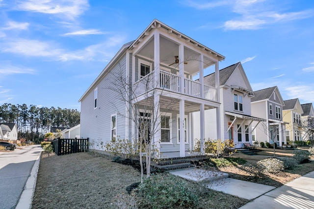 view of front facade featuring ceiling fan, covered porch, a residential view, and a balcony