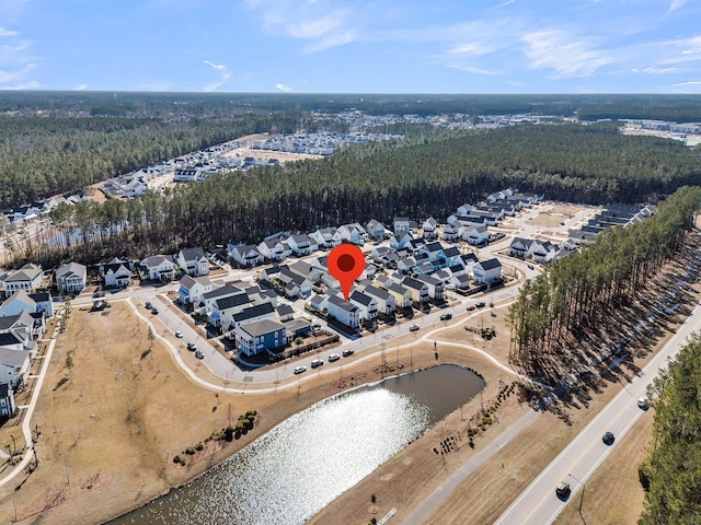 drone / aerial view featuring a water view, a wooded view, and a residential view