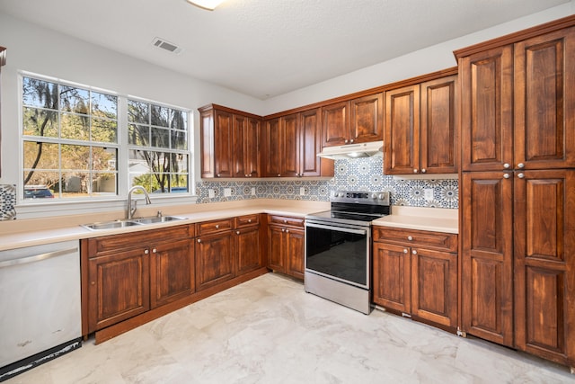 kitchen with backsplash, sink, appliances with stainless steel finishes, and a textured ceiling