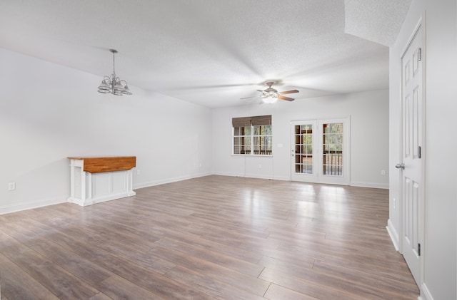 unfurnished living room featuring hardwood / wood-style floors, ceiling fan with notable chandelier, and a textured ceiling