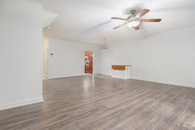 empty room with a textured ceiling, dark wood-type flooring, and ceiling fan with notable chandelier