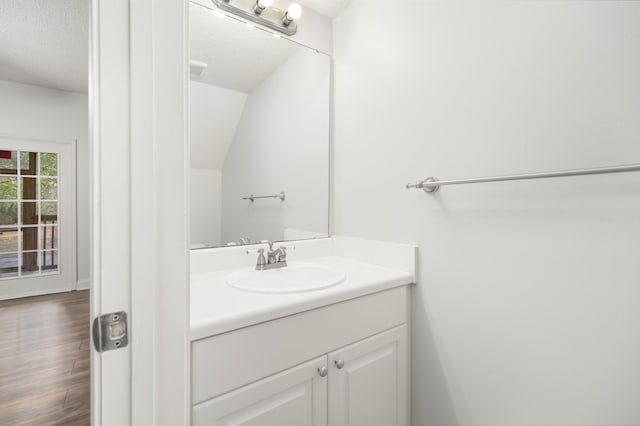 bathroom with hardwood / wood-style flooring, vanity, a textured ceiling, and vaulted ceiling