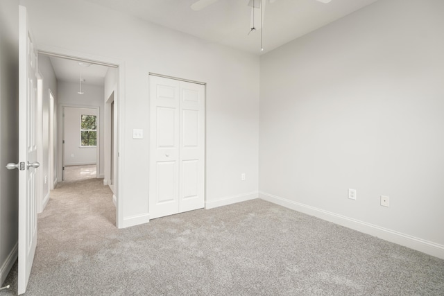 unfurnished bedroom featuring light carpet, a closet, and ceiling fan