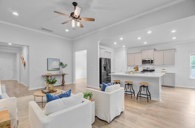 living area with ornamental molding, a ceiling fan, light wood finished floors, recessed lighting, and baseboards