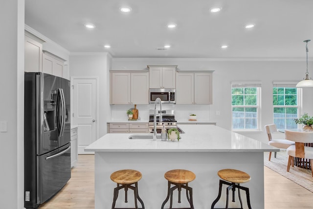 kitchen with appliances with stainless steel finishes, light wood-type flooring, crown molding, a breakfast bar area, and recessed lighting
