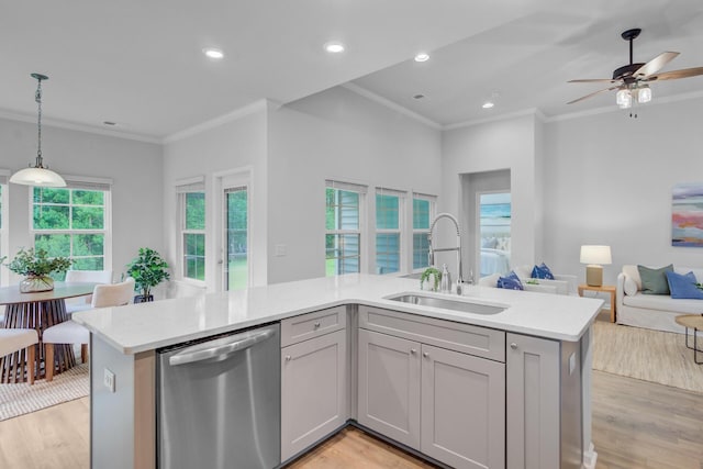 kitchen featuring stainless steel dishwasher, a sink, open floor plan, crown molding, and light wood finished floors