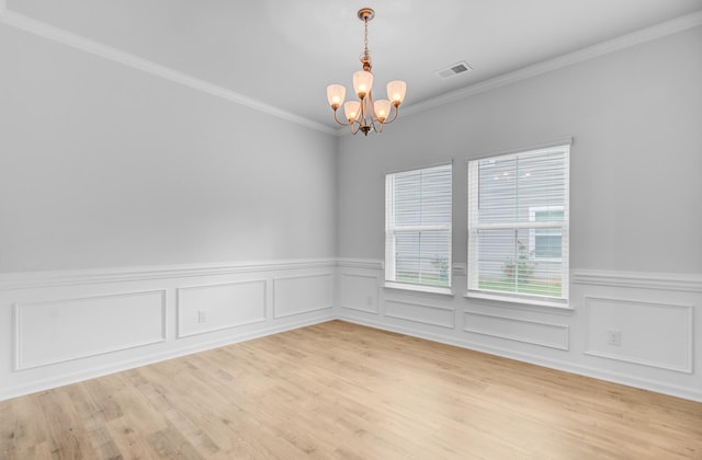 unfurnished room with a chandelier, wainscoting, crown molding, and light wood-style floors