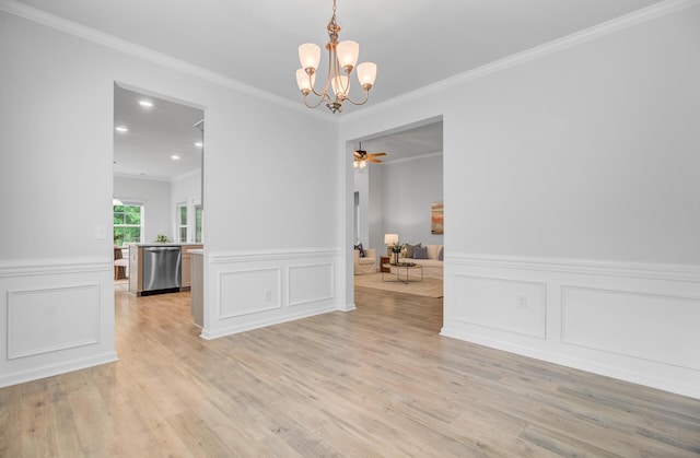 empty room with a chandelier, ornamental molding, light wood-type flooring, a decorative wall, and a wainscoted wall