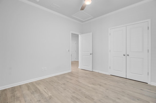 unfurnished bedroom featuring ornamental molding, attic access, light wood-style flooring, baseboards, and a closet