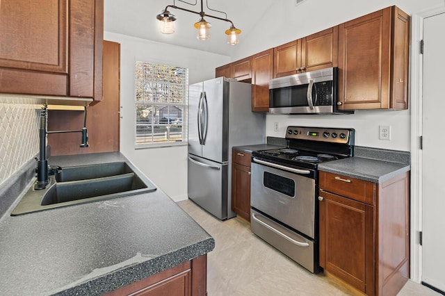 kitchen featuring lofted ceiling, stainless steel appliances, a sink, brown cabinets, and dark countertops