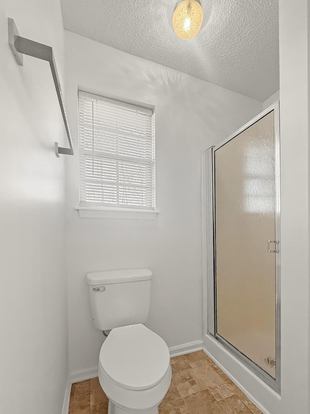 full bath with a shower stall, toilet, and a textured ceiling