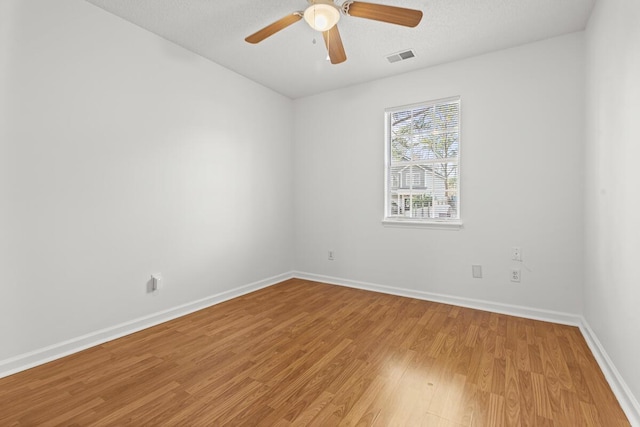 empty room with visible vents, baseboards, a ceiling fan, light wood-style flooring, and a textured ceiling