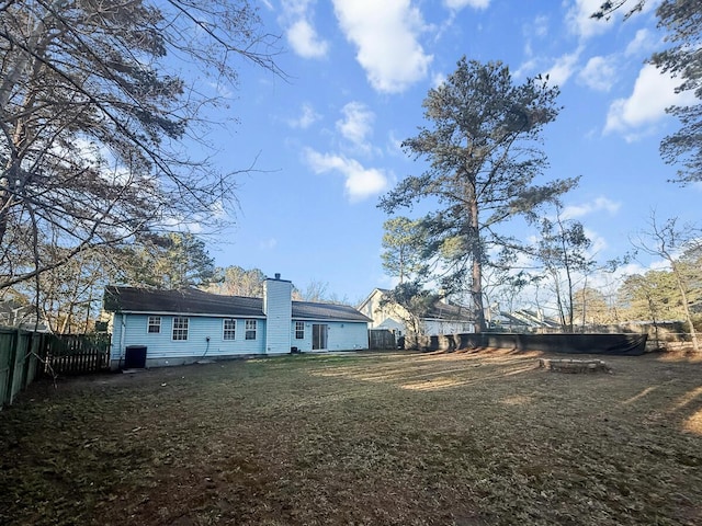 back of house with a fenced backyard, a lawn, and a chimney