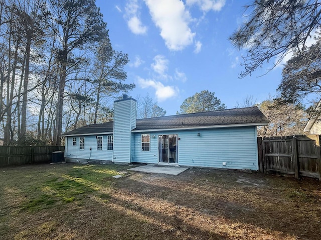 rear view of property featuring a yard, a patio, a chimney, and fence