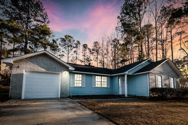 ranch-style home featuring concrete driveway, a lawn, and an attached garage