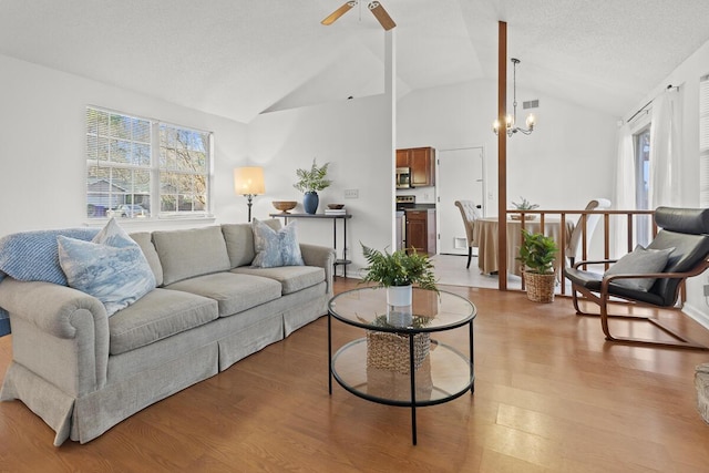 living area with light wood-type flooring, visible vents, vaulted ceiling, and a textured ceiling