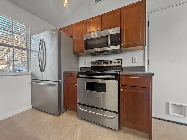 kitchen featuring visible vents, brown cabinetry, dark countertops, lofted ceiling, and stainless steel appliances