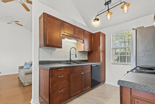 kitchen with black dishwasher, dark countertops, lofted ceiling, freestanding refrigerator, and a sink