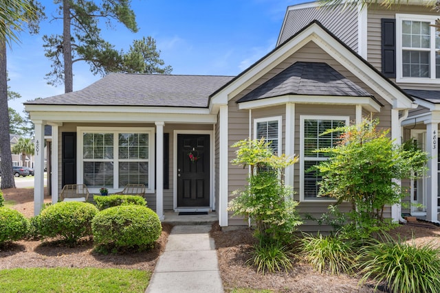 view of exterior entry featuring a shingled roof
