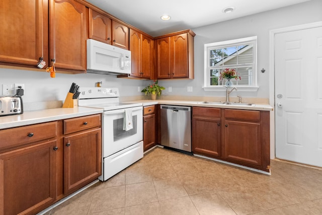 kitchen featuring white appliances, a sink, light countertops, brown cabinetry, and recessed lighting