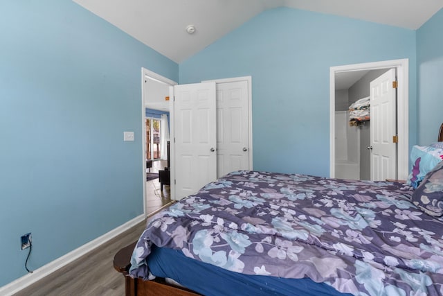 bedroom with vaulted ceiling, wood finished floors, and baseboards