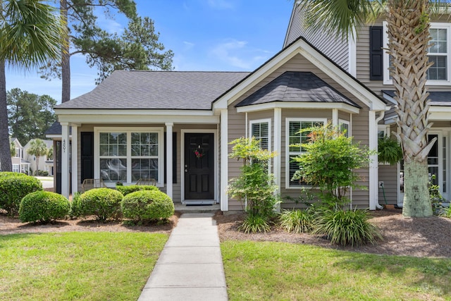 view of front facade with a front lawn and a shingled roof