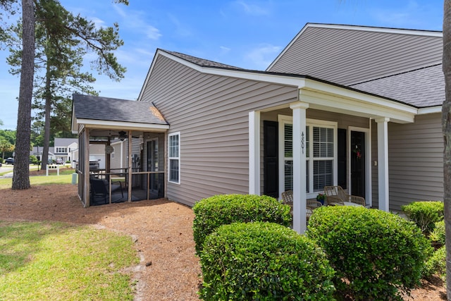 view of side of home featuring roof with shingles and a sunroom