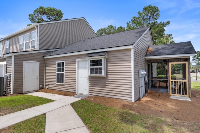 view of front of property featuring a sunroom, a shingled roof, and a front yard