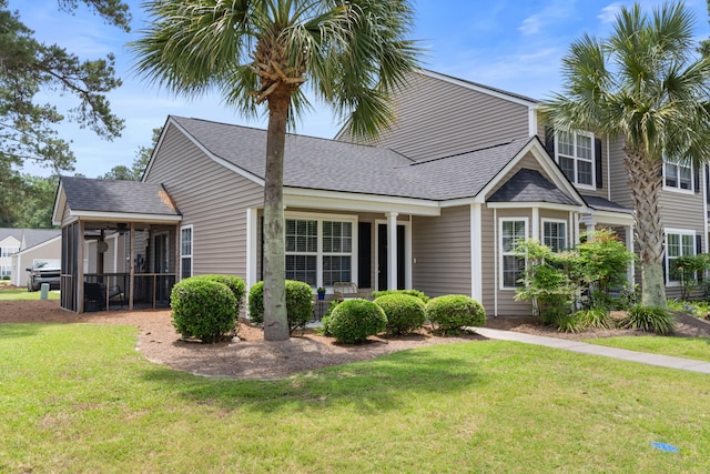 view of front of home featuring a front yard, a sunroom, and a shingled roof