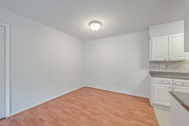 unfurnished dining area with a textured ceiling and light hardwood / wood-style floors