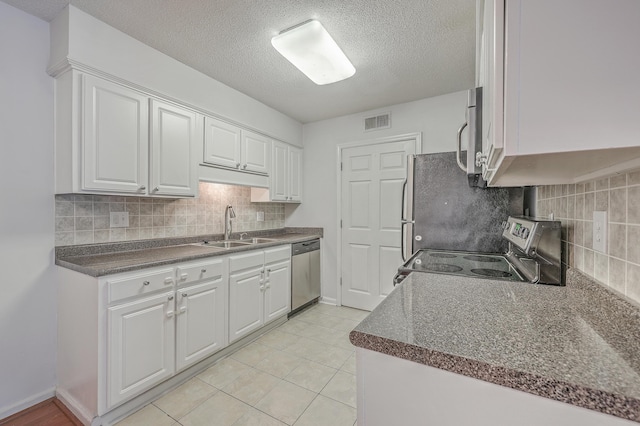 kitchen featuring stainless steel appliances, light tile patterned floors, white cabinets, and sink