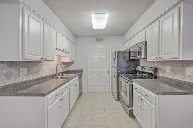 kitchen featuring sink, white cabinetry, a textured ceiling, light tile patterned flooring, and appliances with stainless steel finishes