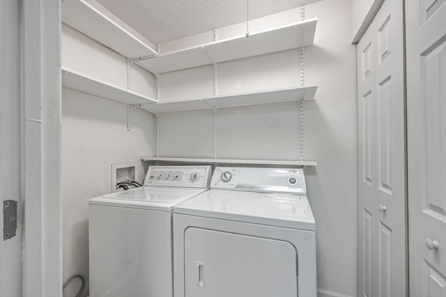 washroom with a textured ceiling and separate washer and dryer