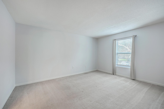 unfurnished room featuring a textured ceiling and light carpet