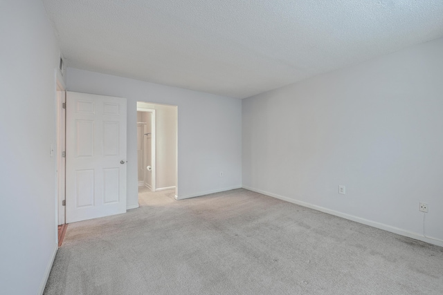 empty room with a textured ceiling and light colored carpet