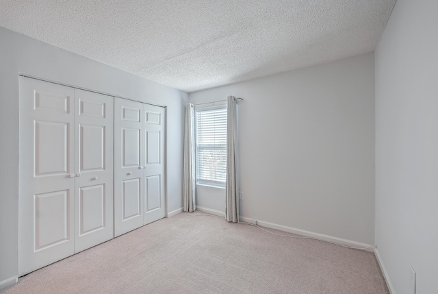 unfurnished bedroom with a textured ceiling, a closet, and light carpet